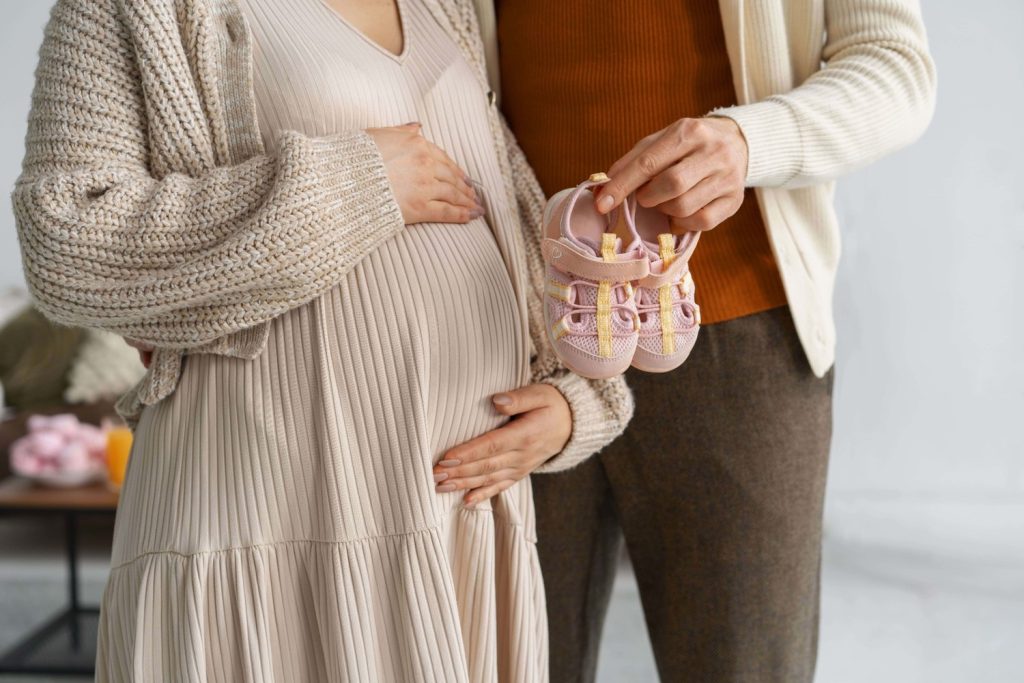 Pasangan sedang berfoto sambil memegang sepatu bayi