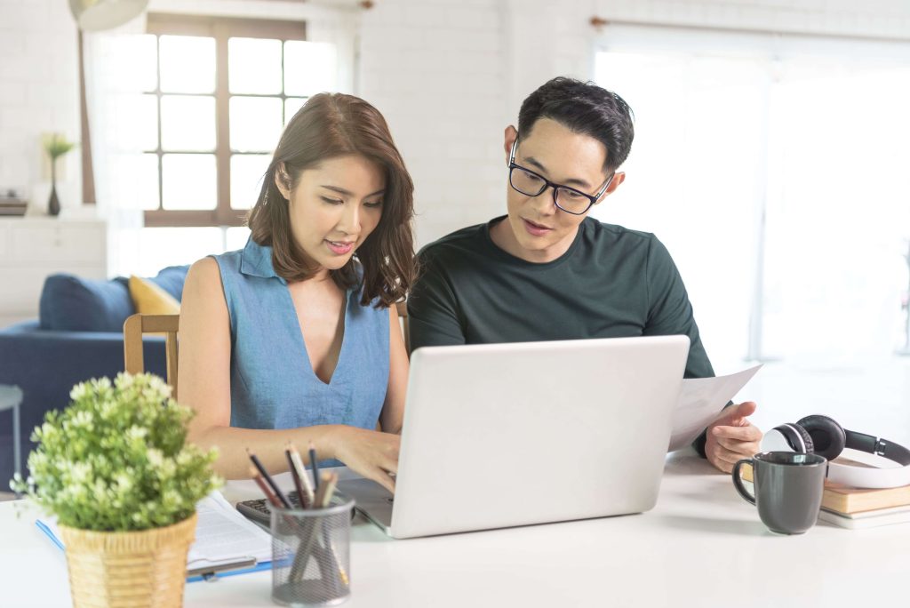 Pasangan Asia sedang menghitung keuangan keluarga di laptop.