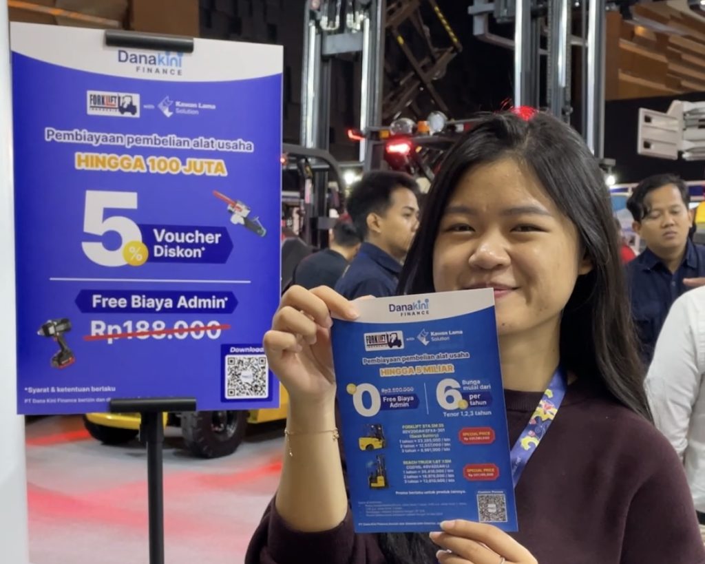 Seorang wanita memegang poster promo Danakini Finance di event Forklift Indonesia 2025