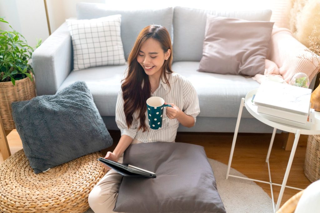 Seorang wanita Asia mencari inspirasi dekor rumah di internet saat duduk di rumah.
