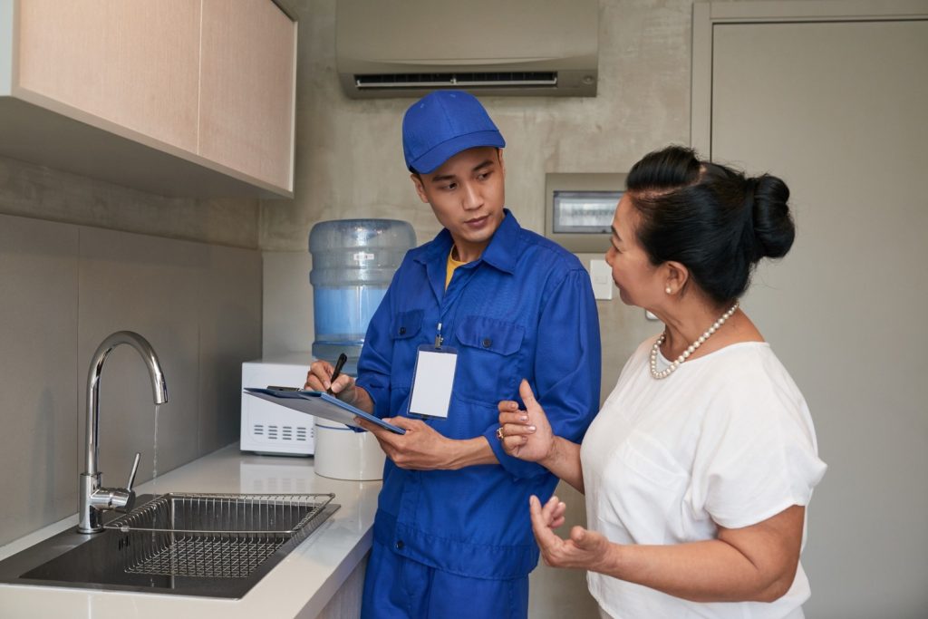 Seorang wanita berbicara dengan tukan reparasi rumah di dapur.