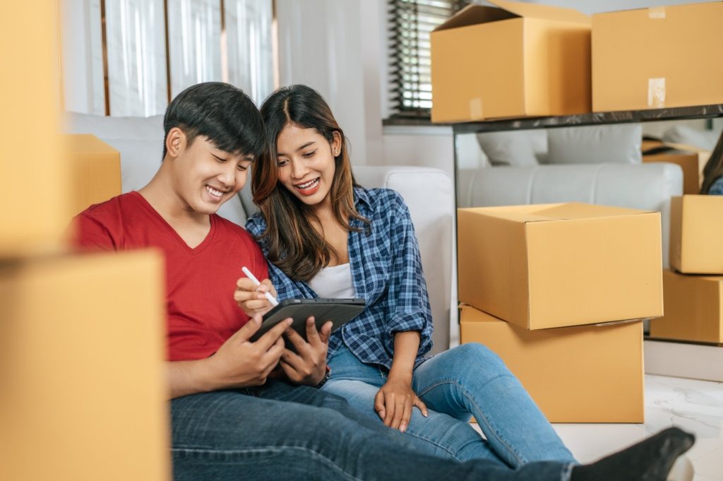 Pasangan Asia sedang menghitung anggaran saat pindahan rumah.