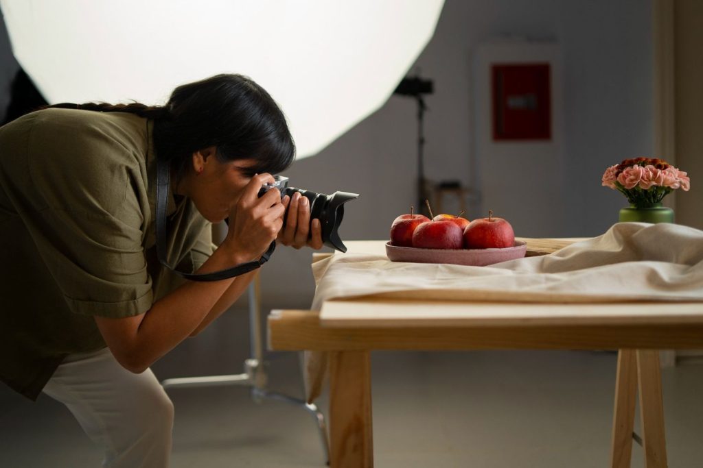 Seorang fotografer sedang memotret sepiring apel.