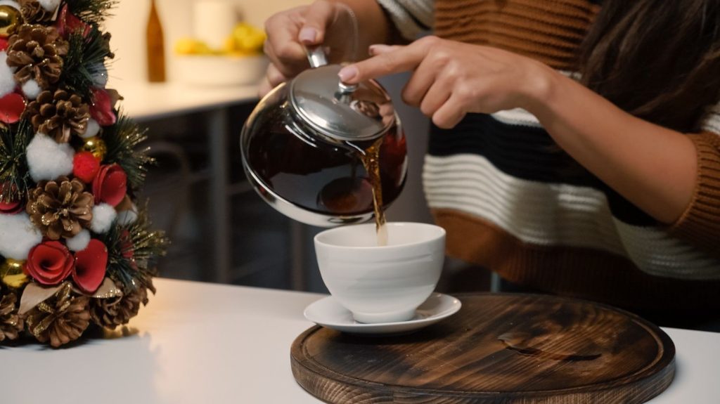 Seseorang menuangkan kopi dari pot ke cangkir.