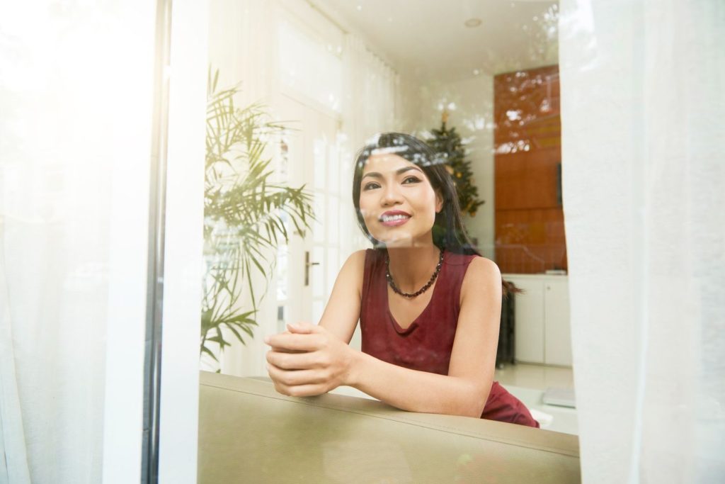 Seorang wanita Asia sedang melihat keluar dari jendela