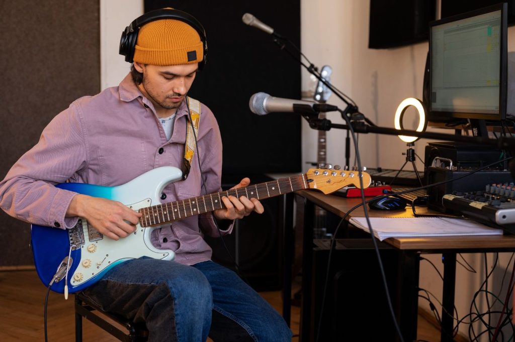 Seorang pria merekam permainan gitar di studio