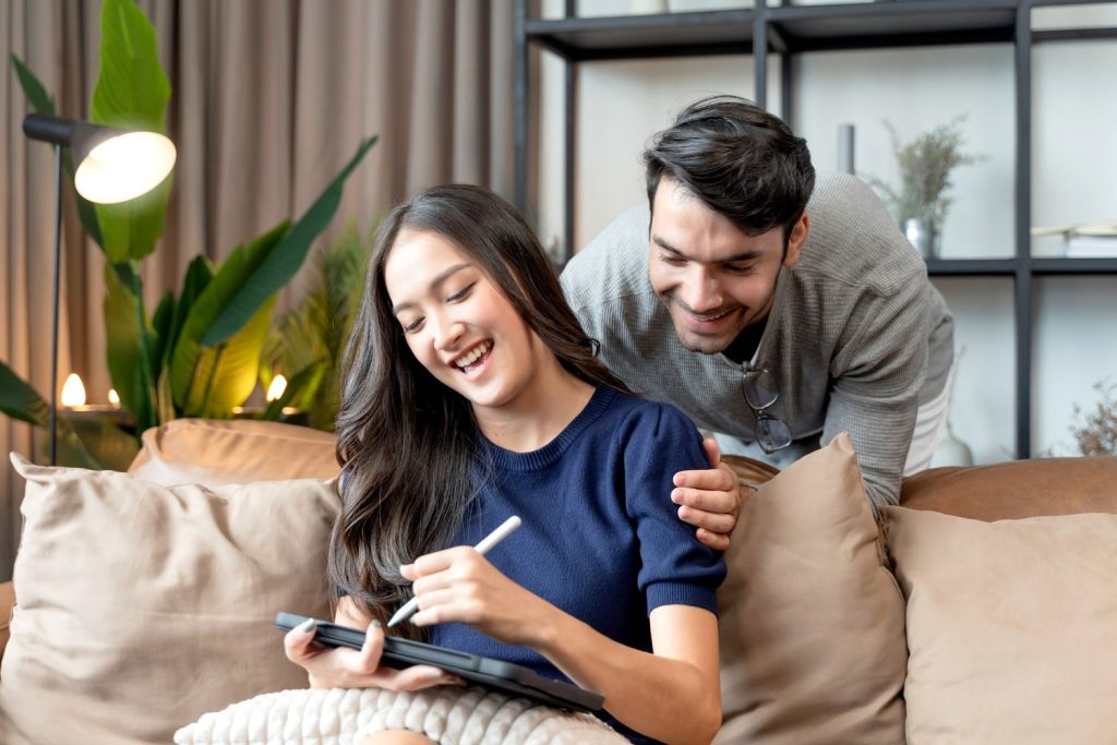 Sepasang suami istri sedang menulis tujuan keuangan bersama-sama