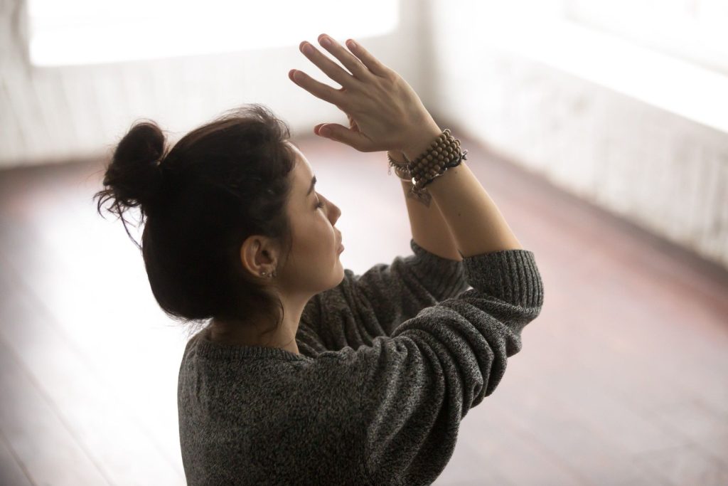 Seorang wanita sedang meditasi di rumah untuk self-healing